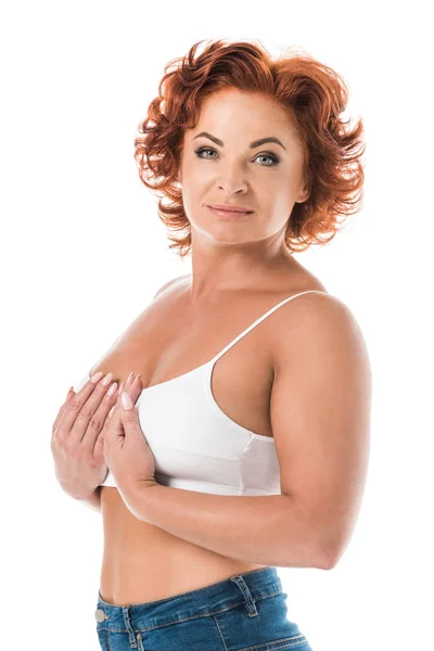 Middle aged woman in bra touching breast and looking at camera isolated on white — Stock Photo
