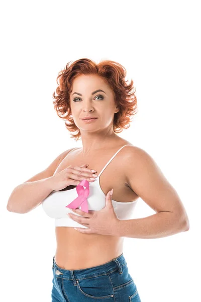 Женщина среднего возраста, проверяющая грудь и смотрящая на камеру, изолированную на белом, концепцию информированности о раке — стоковое фото
