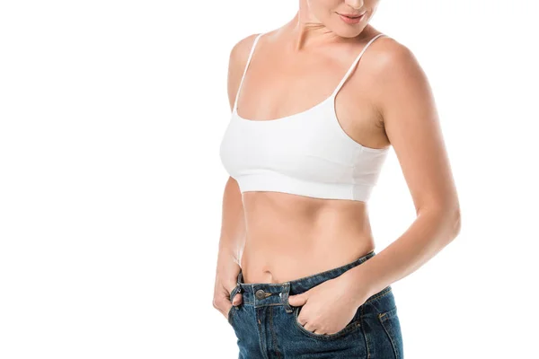 Tiro recortado de mujer sonriente en ropa interior blanca y jeans aislados en blanco - foto de stock