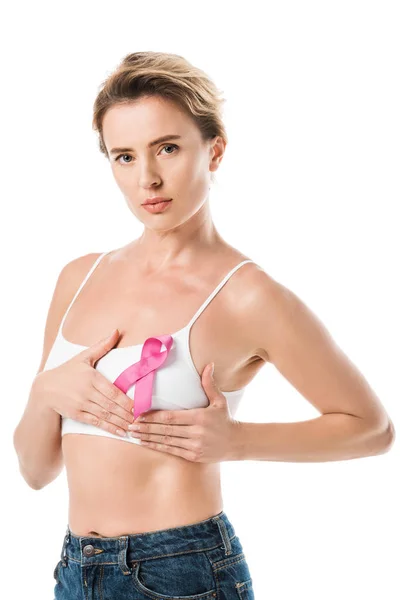 Donna in reggiseno con nastro rosa toccare il seno e guardando la fotocamera isolata su bianco, concetto di consapevolezza del cancro — Foto stock