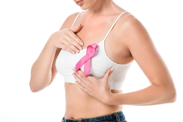 Tiro recortado de la mujer en sujetador con cinta rosa comprobar mama aislado en blanco, concepto de conciencia del cáncer - foto de stock