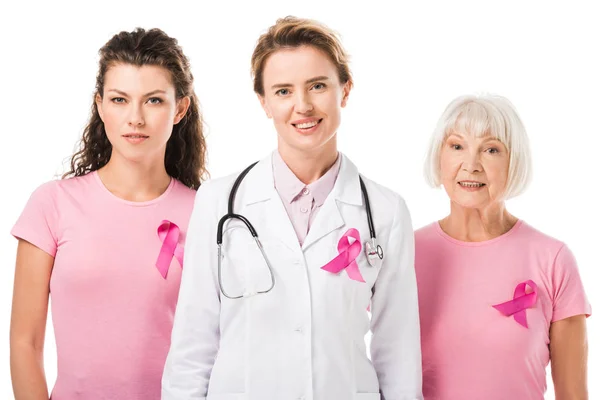 Médico y mujeres con cintas de conciencia de cáncer de mama sonriendo a la cámara aislada en blanco - foto de stock