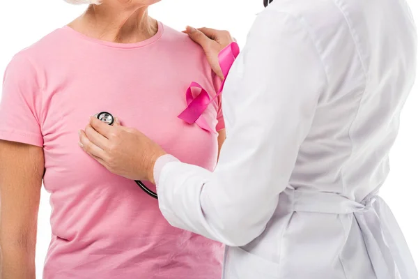 Plan recadré du médecin avec stéthoscope vérifier la santé de la femme âgée avec un ruban de sensibilisation au cancer du sein isolé sur blanc — Photo de stock