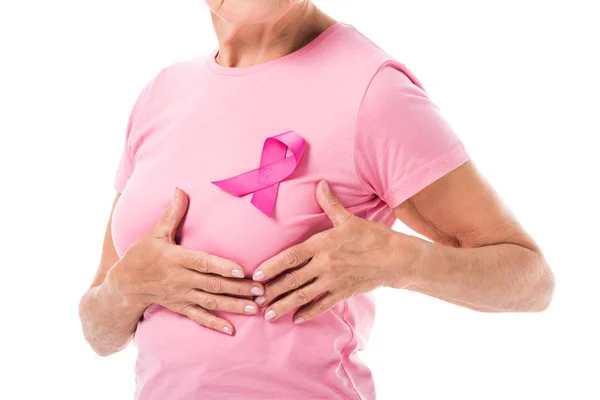 Tiro recortado de mujer mayor con cinta rosa tocando mama aislado en blanco, concepto de cáncer - foto de stock