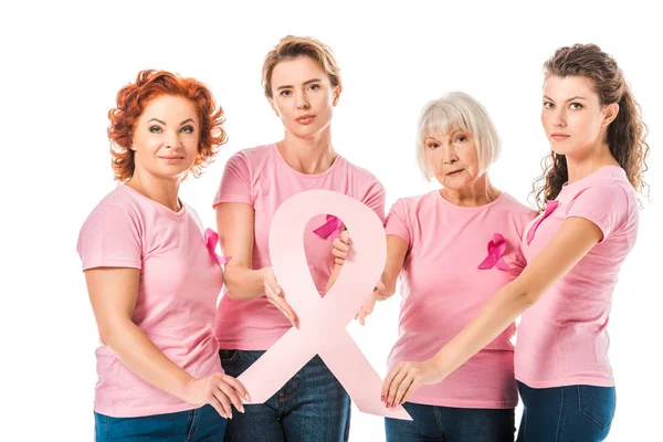 Mujeres en camisetas de color rosa que sostienen la cinta de conciencia del cáncer de mama y mirando a la cámara aislada en blanco - foto de stock