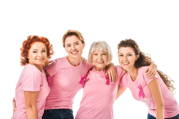 Веселі жінки в рожевих футболках зі стрічками поінформованості про рак молочної залози, посміхаються на камеру ізольовані на білому — стокове фото