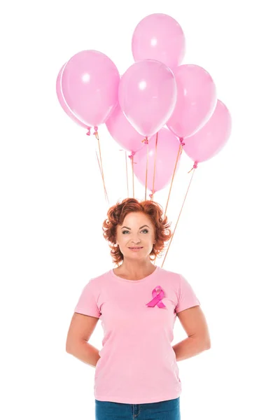 Mature woman holding bunch of pink balloons and smiling at camera isolated on white, breast cancer concept — Stock Photo