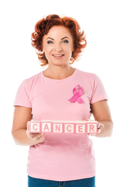 Donna con nastro rosa con blocchi di contenimento con parola cancro e sorridente alla fotocamera isolata su bianco — Foto stock