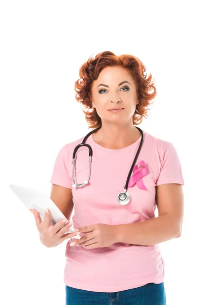 Mature woman with stethoscope holding digital tablet and looking at camera isolated on white, breast cancer awareness concept — Stock Photo