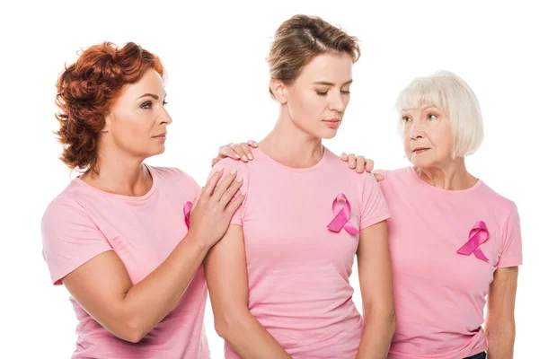 Women in pink t-shirts supporting upset woman isolated on white, breast cancer concept — Stock Photo