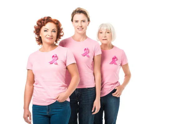 Smiling women with pink ribbons standing together and looking at camera isolated on white, breast cancer awareness concept — Stock Photo