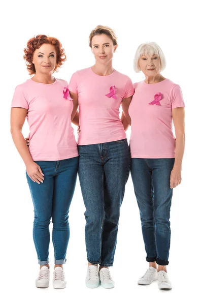 Donne con nastri rosa in piedi insieme e guardando la fotocamera isolata sul bianco, concetto di consapevolezza del cancro al seno — Foto stock
