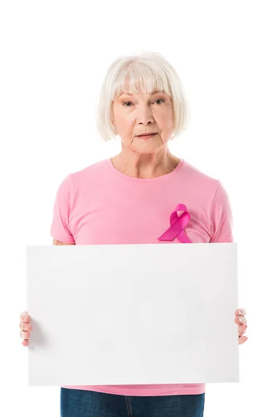 Anziana donna in t-shirt rosa con nastro di consapevolezza del cancro al seno tenendo banner in bianco e guardando la fotocamera isolata su bianco — Foto stock