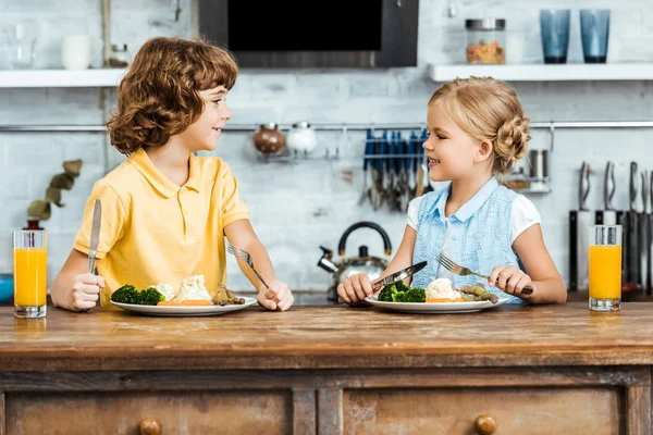 Cute happy children eating healthy vegetables and smiling each other — Stock Photo