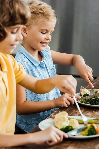 Cropped shot of cute smiling children eating healthy vegetables — Stock Photo