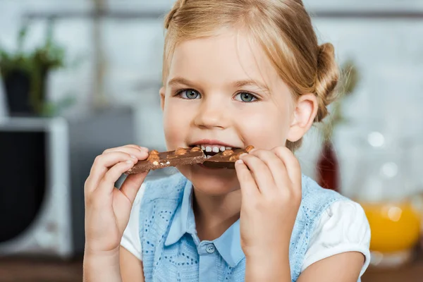 Adorabile bambino mangiare delizioso cioccolato e sorridere alla fotocamera — Foto stock