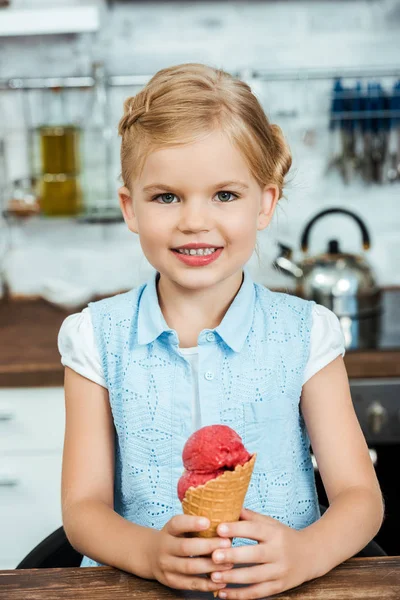 Garoto feliz bonito segurando delicioso cone de sorvete doce e sorrindo para a câmera — Fotografia de Stock
