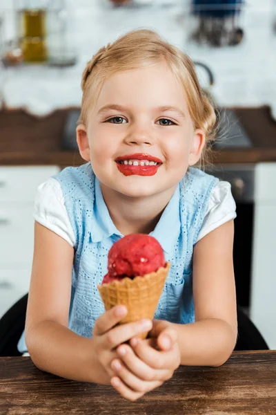 Adorable feliz niño sosteniendo delicioso dulce helado cono y sonriendo a la cámara - foto de stock