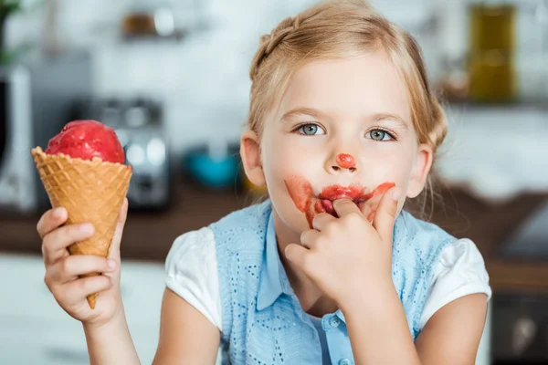 Entzückendes kleines Kind leckt Finger, während es süßes Eis isst und in die Kamera schaut — Stockfoto