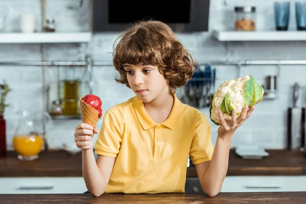 Boy holding delicious sweet ice cream and healthy cauliflower — Stock Photo