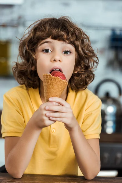 Adorable niño comiendo delicioso helado y mirando a la cámara - foto de stock