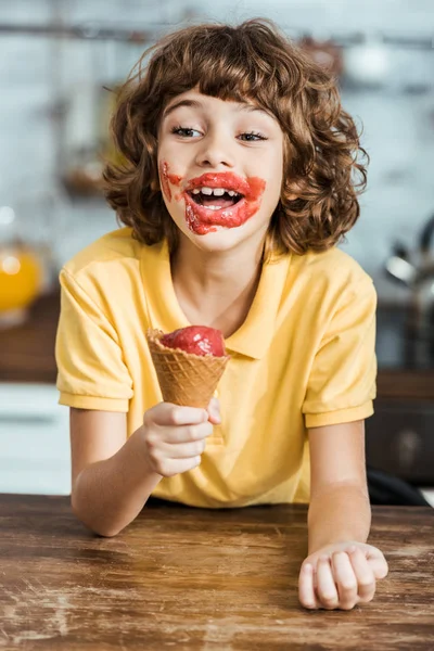 Adorável menino feliz com sorvete na cara segurando delicioso cone de sorvete — Fotografia de Stock