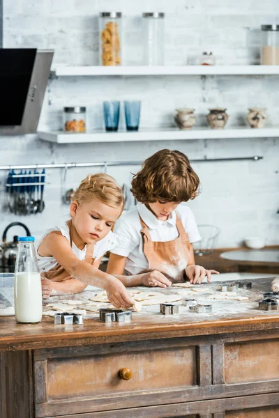 Crianças adoráveis em aventais preparando biscoitos juntos — Fotografia de Stock