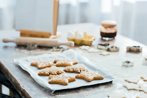 Nahaufnahme von köstlichen Ingwerplätzchen auf Backblech, Kochbuch und Zutaten auf dem Tisch — Stockfoto