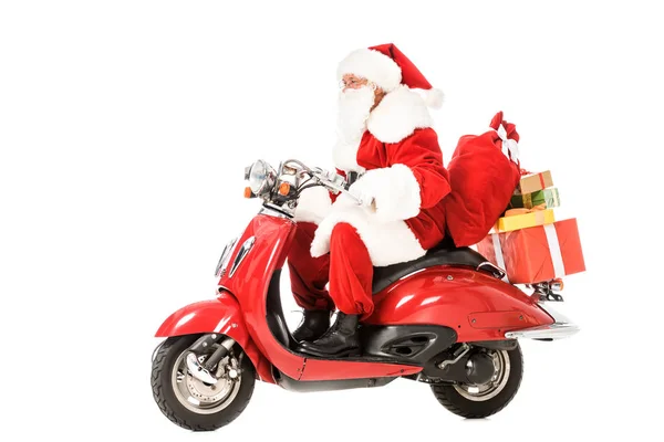 Вид сбоку на Санта-Клауса на винтажном красном скутере с мешками и подарочными коробками, изолированными на белом — стоковое фото