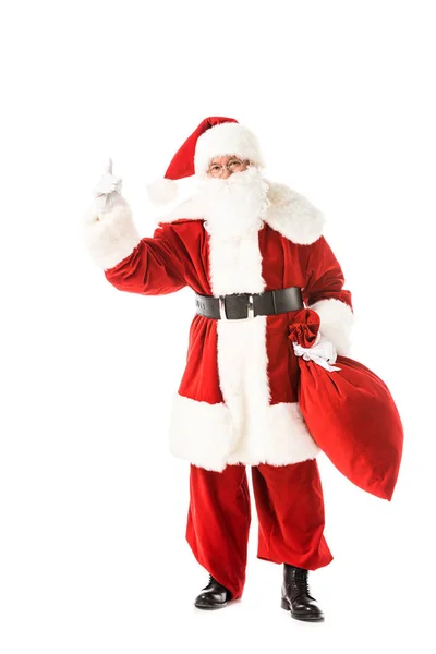Санта Клаус тримає мішок і вказує вгору, дивлячись на камеру ізольовано на білому — стокове фото