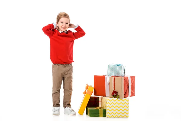 Smiling little kid with pile of christmas gifts isolated on white — Stock Photo