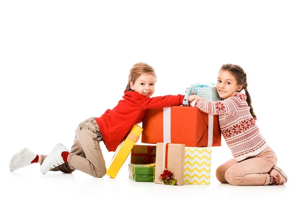 Happy little kids sitting on floor with pile of christmas gifts isolated on white — Stock Photo