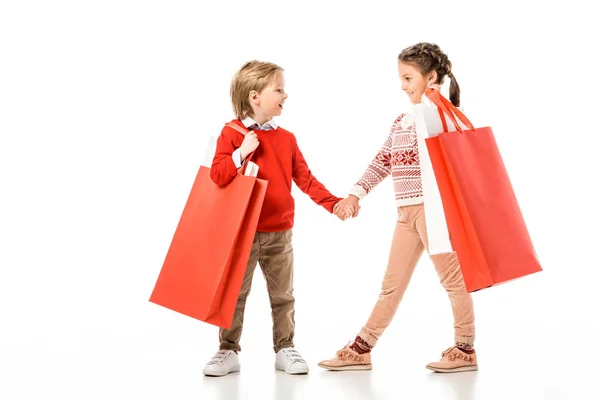 Happy little kids in christmas sweater holding big paper bags isolated on white — Stock Photo