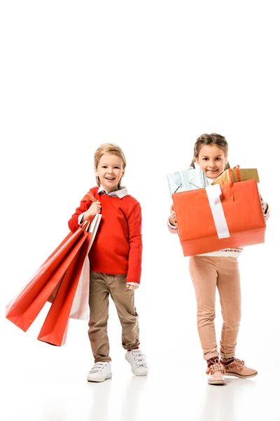 Glückliche kleine Kinder mit Papiertüten und Weihnachtsgeschenken isoliert auf weiß — Stockfoto