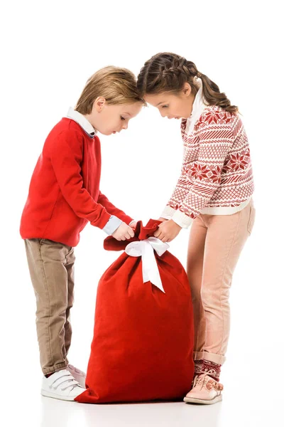 Crianças animadas olhando para o saco de presente de Papai Noel isolado no branco — Fotografia de Stock