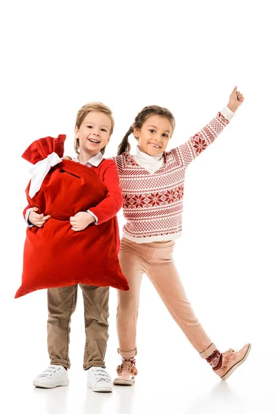 Aufgeregte kleine Kinder mit Weihnachtsmann-Geschenktüte, die isoliert auf weiß in die Kamera schauen — Stockfoto