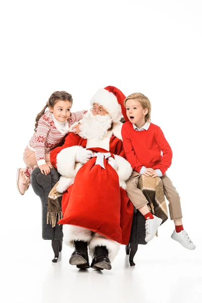 Niños emocionados y santa sentado en sillón juntos aislados en blanco - foto de stock