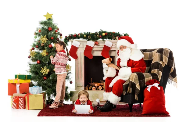 Glückliche Kinder und der Weihnachtsmann blicken in die Kamera, während sie die Zeit zusammen isoliert auf Weiß verbringen — Stockfoto