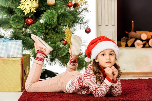 Beautiful little child lying on carpet near christmas tree — Stock Photo