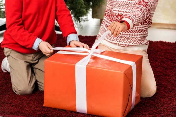 Plan recadré d'enfants ouvrant cadeau de Noël rouge — Photo de stock