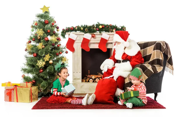 Crianças felizes e santa sentado na frente da lareira juntos isolados no branco — Fotografia de Stock