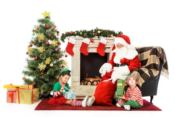 Niños y santa sentado frente a la chimenea juntos aislados en blanco - foto de stock