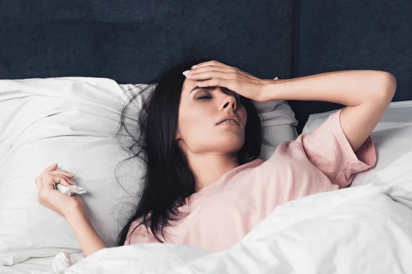 Mujer joven enferma con alta temperatura acostada en la cama - foto de stock