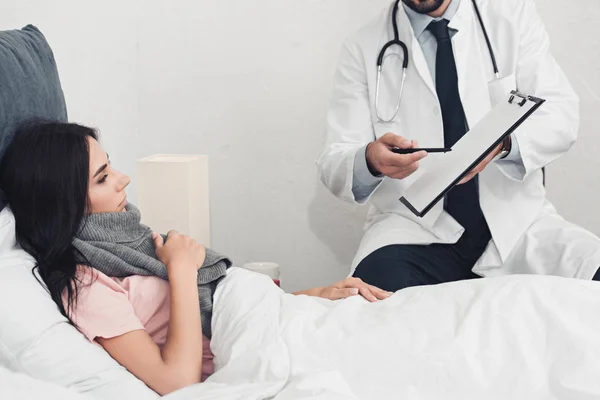 Tiro recortado de médico mostrando prancheta com documentos para paciente para assinar — Fotografia de Stock