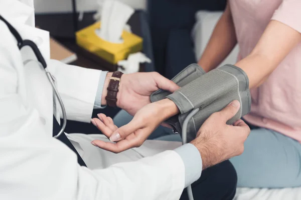 Colpo ritagliato del medico che misura la pressione sanguigna del paziente — Foto stock