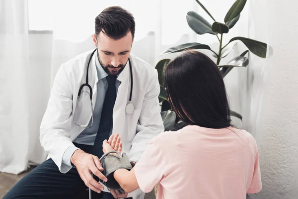 Schöner junger Arzt misst Blutdruck des Patienten — Stockfoto