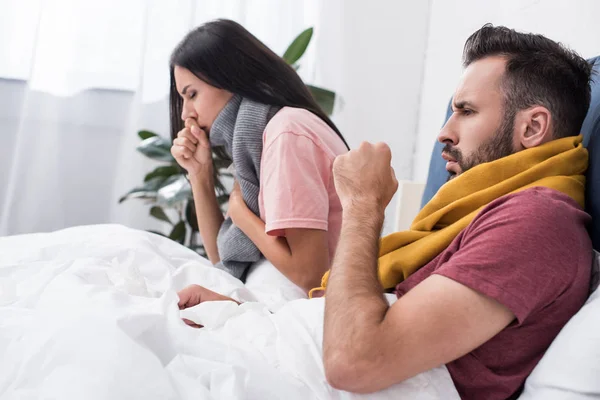 Malato giovane coppia con tosse seduta a letto — Foto stock