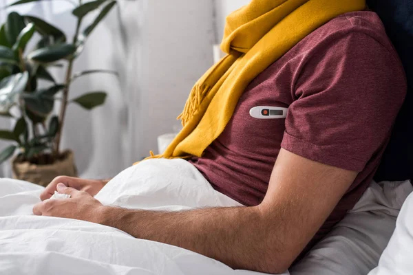 Tiro recortado do homem doente que mede a temperatura com o termômetro eletrônico na cama — Fotografia de Stock