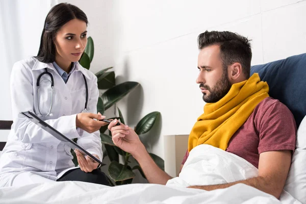 Жінка-лікар дає буфер обміну з документами для пацієнта, лежачи в ліжку — стокове фото