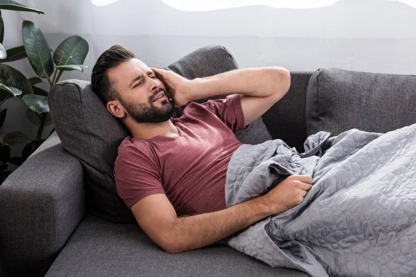 Farce jeune homme avec mal de tête couché sur le canapé — Photo de stock